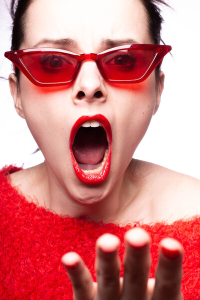 молодая женщина в красных солнечных очках, красная помада, красный свитер

