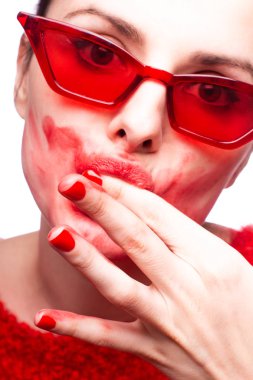 Kırmızı kazaklı ve kırmızı gözlüklü bir kızın yüzüne ruj bulaşmış.