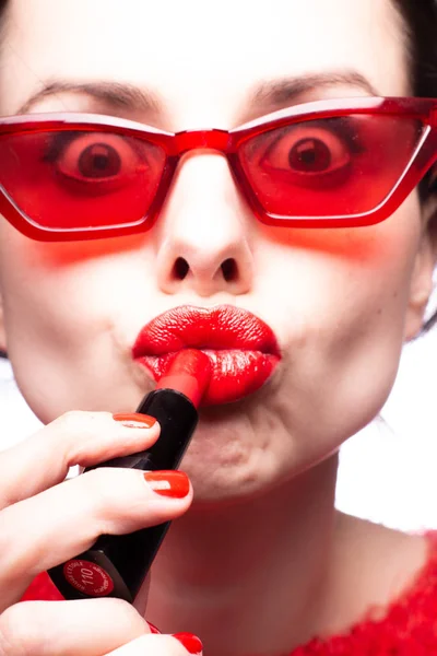Dziewczyna Czerwonym Swetrze Czerwonych Okularach Maluje Usta Czerwoną Szminką — Zdjęcie stockowe
