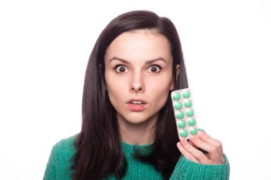 Yeşil kazaklı güzel bir kız elinde bir paket hap tutuyor.