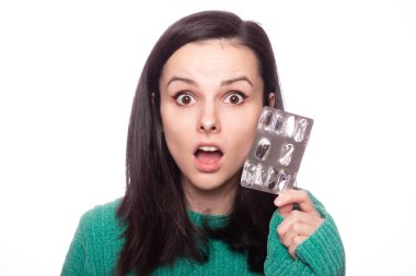 Yeşil kazaklı güzel bir kız elinde bir paket hap tutuyor.