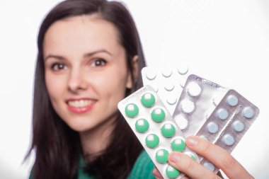 Yeşil kazaklı güzel bir kız elinde bir paket hap tutuyor.