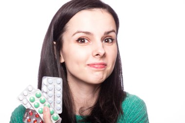 Yeşil kazaklı güzel bir kız elinde bir paket hap tutuyor.