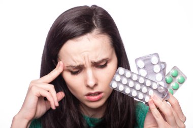 Yeşil kazaklı güzel bir kız elinde bir paket hap tutuyor.