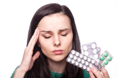 Yeşil kazaklı güzel bir kız elinde bir paket hap tutuyor.