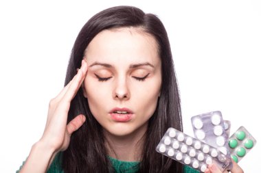 Yeşil kazaklı güzel bir kız elinde bir paket hap tutuyor.