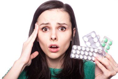 Yeşil kazaklı güzel bir kız elinde bir paket hap tutuyor.