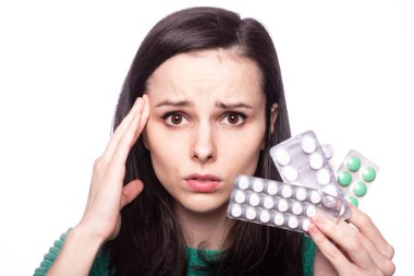 Yeşil kazaklı güzel bir kız elinde bir paket hap tutuyor.