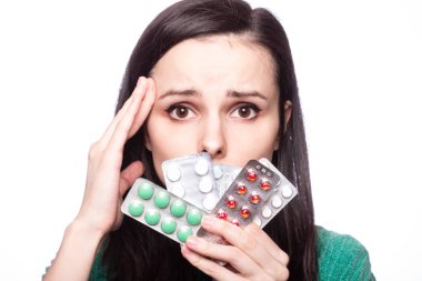 Yeşil kazaklı güzel bir kız elinde bir paket hap tutuyor.