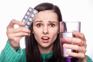 Güzel kız elinde bir bardak su ve hap tutuyor.