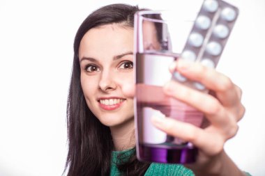 Güzel kız elinde bir bardak su ve hap tutuyor.