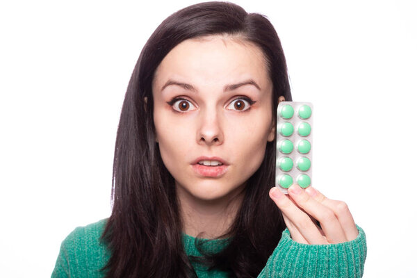 beautiful young girl in a green sweater holding a pack of pills