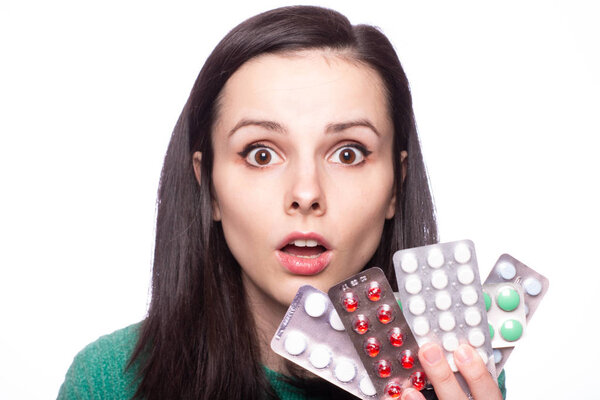 beautiful young girl in a green sweater holding a pack of pills