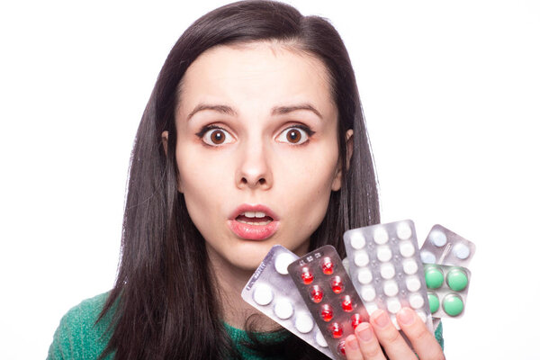 beautiful young girl in a green sweater holding a pack of pills