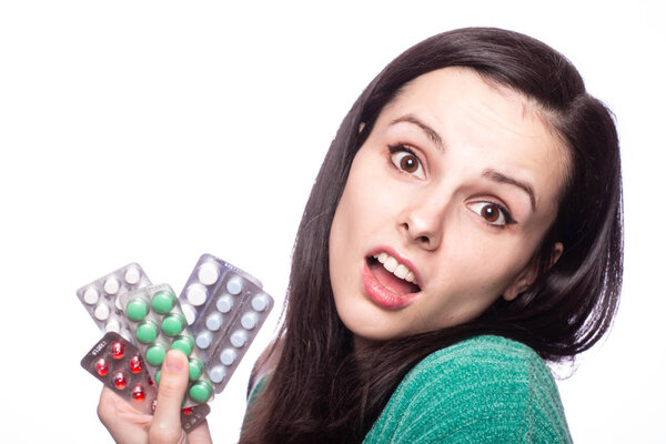 красивая молодая девушка в зеленом свитере с пачкой таблеток
