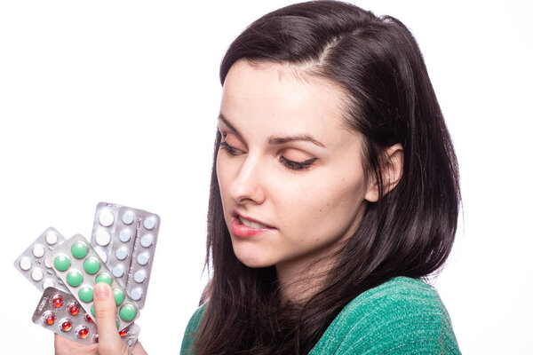 красивая молодая девушка в зеленом свитере с пачкой таблеток
