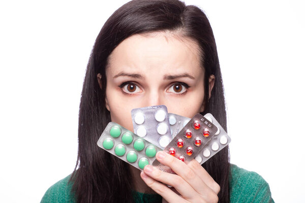 beautiful young girl in a green sweater holding a pack of pills