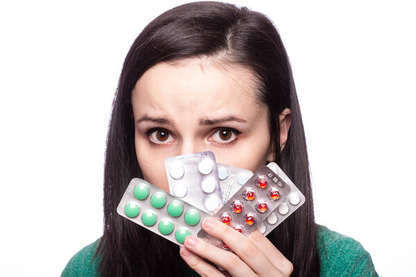 красивая молодая девушка в зеленом свитере с пачкой таблеток
