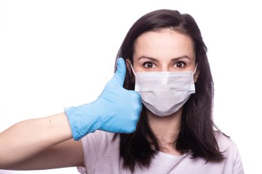 Yüzünde tıbbi maske, ellerinde eldivenler olan genç bir kadın.