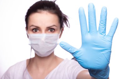 Yüzünde tıbbi maske, ellerinde eldivenler olan genç bir kadın.