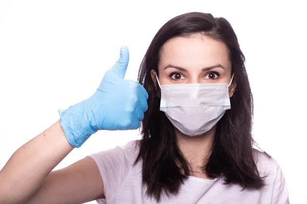 Yüzünde tıbbi maske, ellerinde eldivenler olan genç bir kadın.