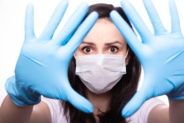 Yüzünde tıbbi maske, ellerinde eldivenler olan genç bir kadın.