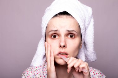 Güzel genç bir kadın dişlerini fırçalıyor, acı çekiyor.