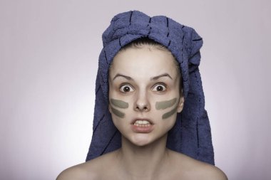Kafasında havlu ve yüzünde maske olan genç bir kadın.