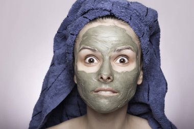 Kafasında havlu ve yüzünde maske olan genç bir kadın.