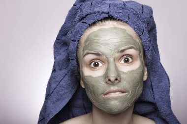 Kafasında havlu ve yüzünde maske olan genç bir kadın.
