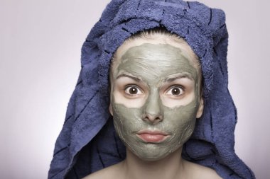 Kafasında havlu ve yüzünde maske olan genç bir kadın.