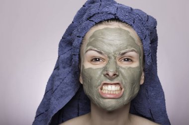 Kafasında havlu ve yüzünde maske olan genç bir kadın.