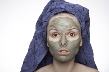 Kafasında havlu ve yüzünde maske olan genç bir kadın.