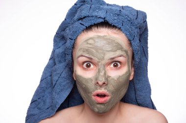 Kafasında havlu ve yüzünde maske olan genç bir kadın.