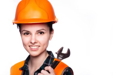 Güzel genç kız miğferli işçi elinde bir İngiliz anahtarı tutuyor.