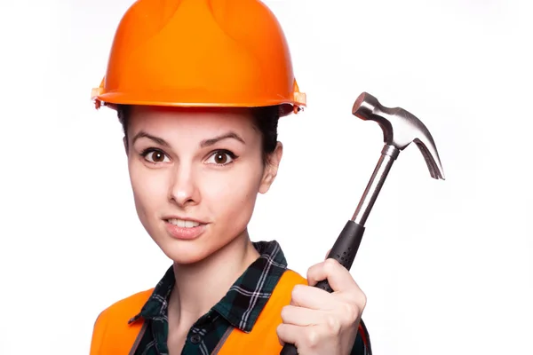 beautiful young girl worker in a helmet holds a hammer in his hand