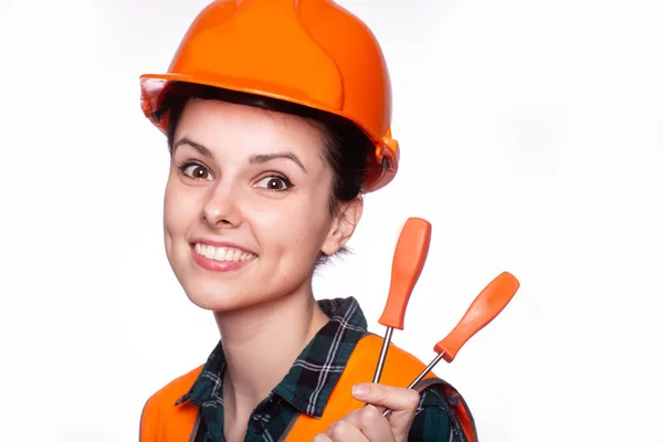 beautiful young girl worker in a helmet holds a screwdriver in his hand