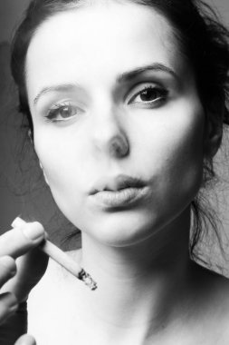 Ağzında sigarayla güzel bir genç kız, siyah beyaz bir fotoğraf.