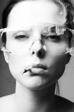 Güvenlik gözlüklü güzel bir kız ağzında sigara, siyah beyaz bir fotoğraf.