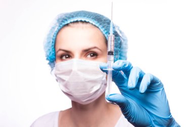 Gözlüklü ve eldivenli genç bir kız elinde bir şırınga tutuyor.