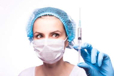 Gözlüklü ve eldivenli genç bir kız elinde bir şırınga tutuyor.