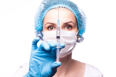 Gözlüklü ve eldivenli genç bir kız elinde bir şırınga tutuyor.