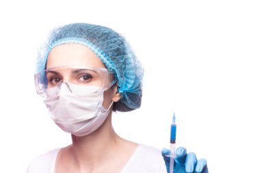 Tıp maskeli, gözlüklü ve eldivenli genç bir kız elinde mavi sıvı bir şırınga tutuyor.