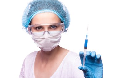 Tıp maskeli, gözlüklü ve eldivenli genç bir kız elinde mavi sıvı bir şırınga tutuyor.