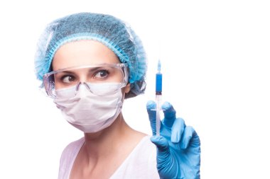 Tıp maskeli, gözlüklü ve eldivenli genç bir kız elinde mavi sıvı bir şırınga tutuyor.