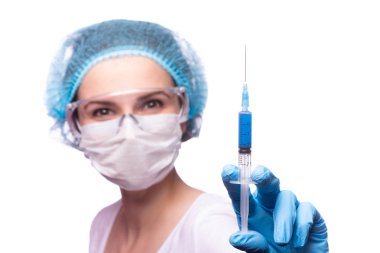 Tıp maskeli, gözlüklü ve eldivenli genç bir kız elinde mavi sıvı bir şırınga tutuyor.