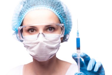 Tıp maskeli, gözlüklü ve eldivenli genç bir kız elinde mavi sıvı bir şırınga tutuyor.