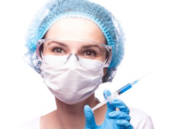 Tıp maskeli, gözlüklü ve eldivenli genç bir kız elinde mavi sıvı bir şırınga tutuyor.