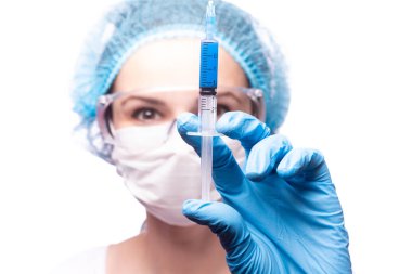 Tıp maskeli, gözlüklü ve eldivenli genç bir kız elinde mavi sıvı bir şırınga tutuyor.