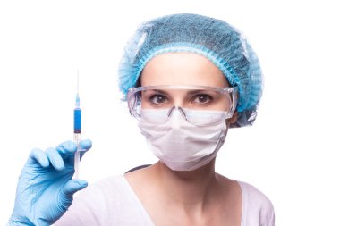 Tıp maskeli, gözlüklü ve eldivenli genç bir kız elinde mavi sıvı bir şırınga tutuyor.